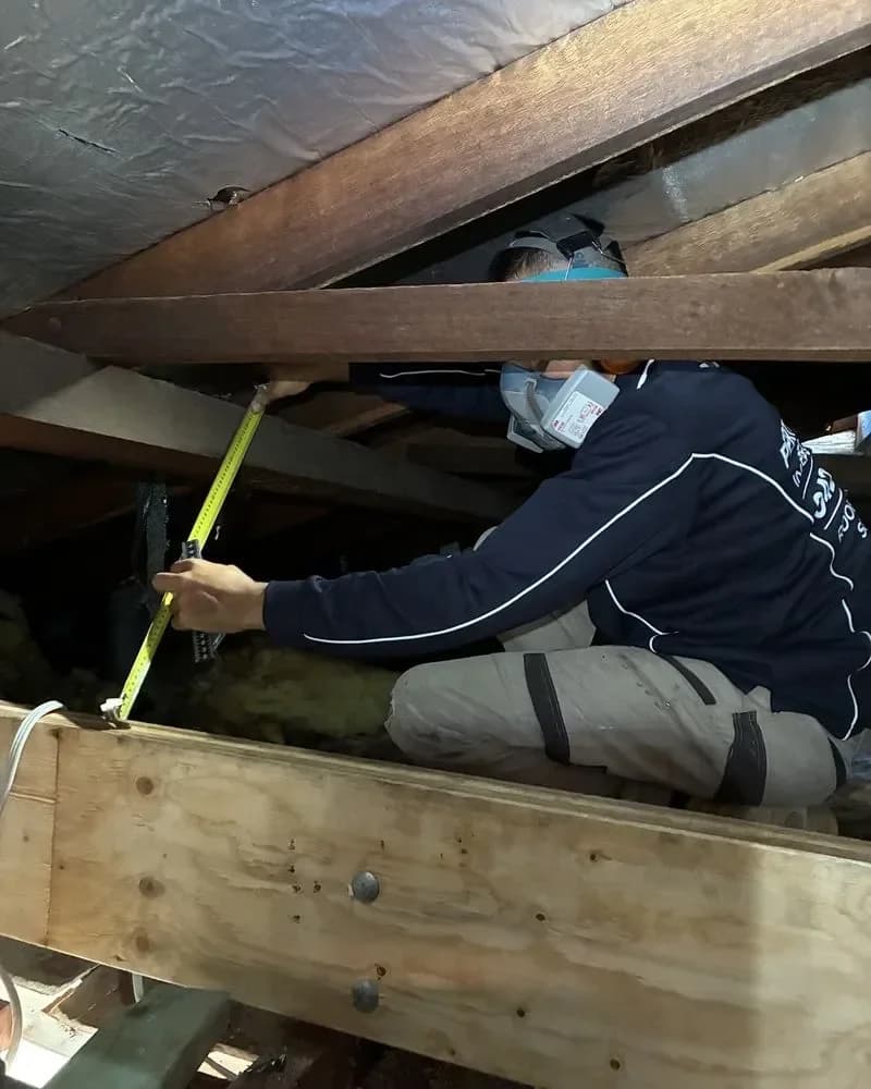 Tradesperson measuring up a defect in a roof cavity