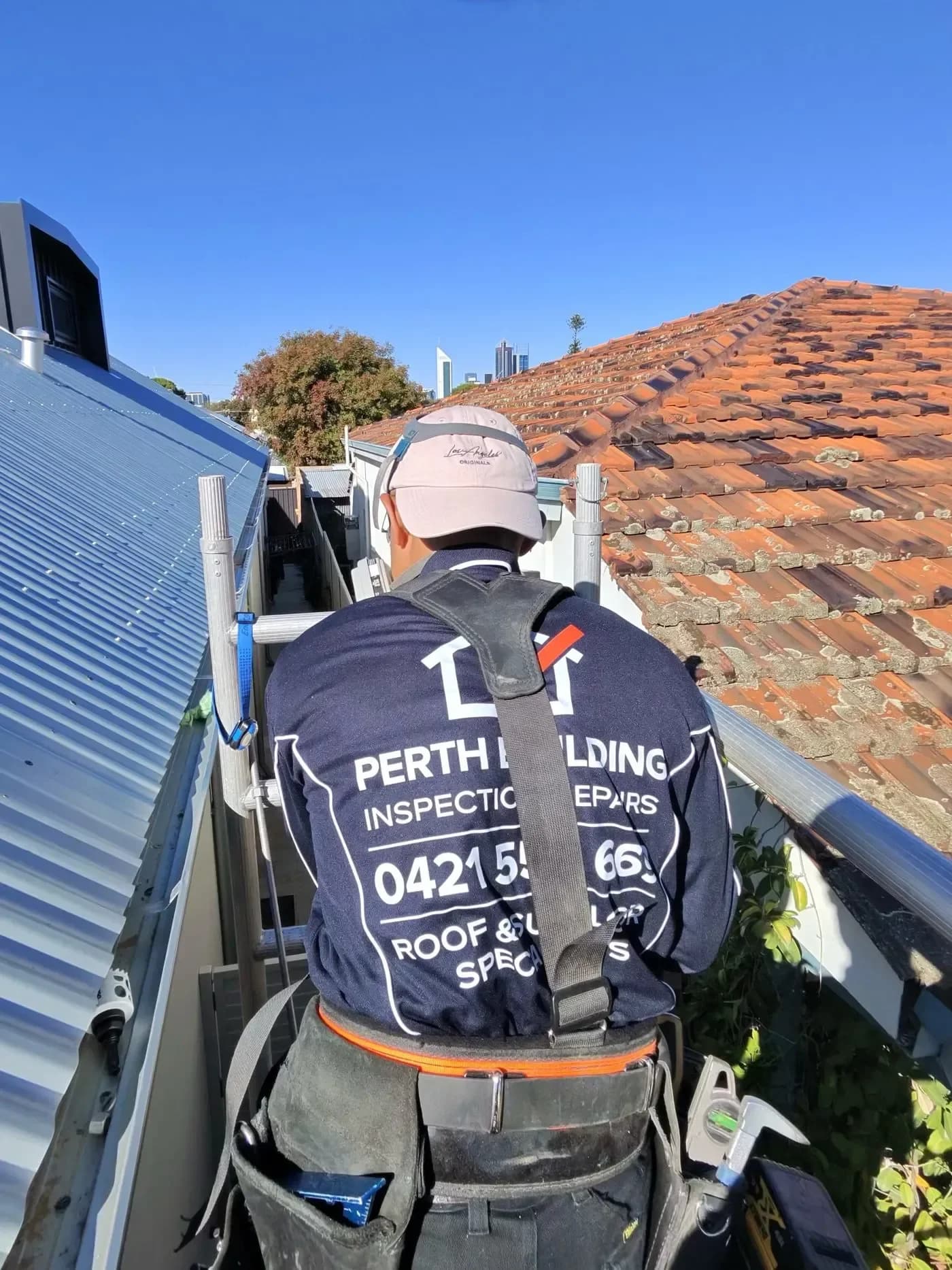 A Perth Building Inspection Repairs tradesperson working at height on a tile roof